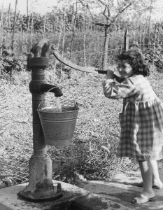 Campagna Toscana Una dolce bambina riempie il secchio di acqua dalla faticosa pompa